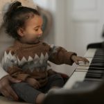 girl in brown sweater playing piano